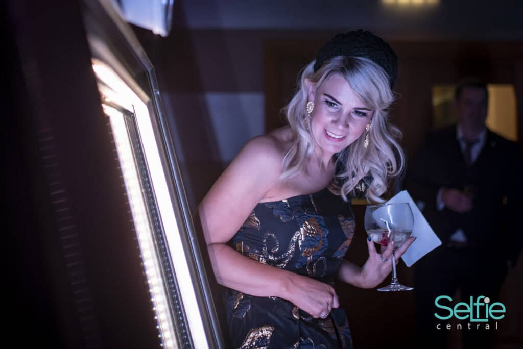 Woman using photo booth at Auckland event for fun selfies.
