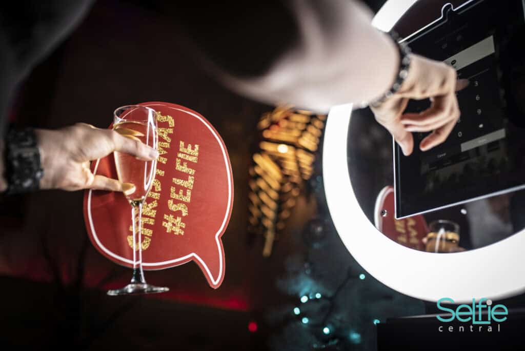 Person using photo booth at Auckland event with selfie props and ring light.