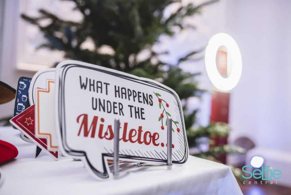 Christmas-themed photo booth sign with mistletoe message at Auckland event.